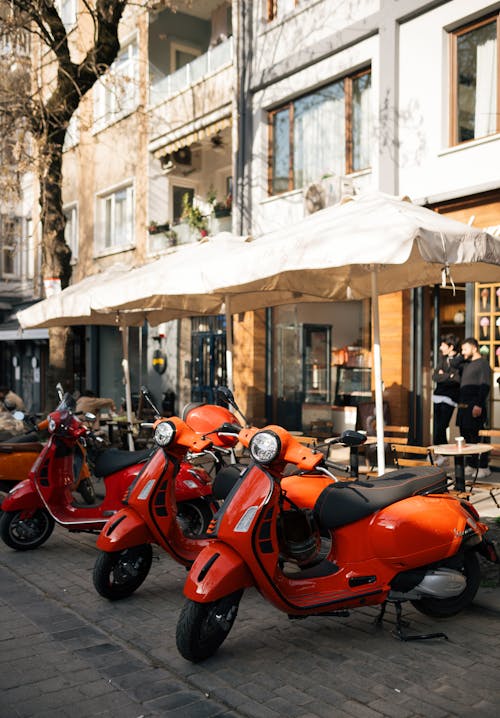 A row of orange scooters parked on a sidewalk