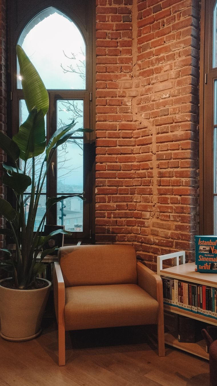 Armchair beside an arched window in a warm brick room — photo by Feyza on Pexels