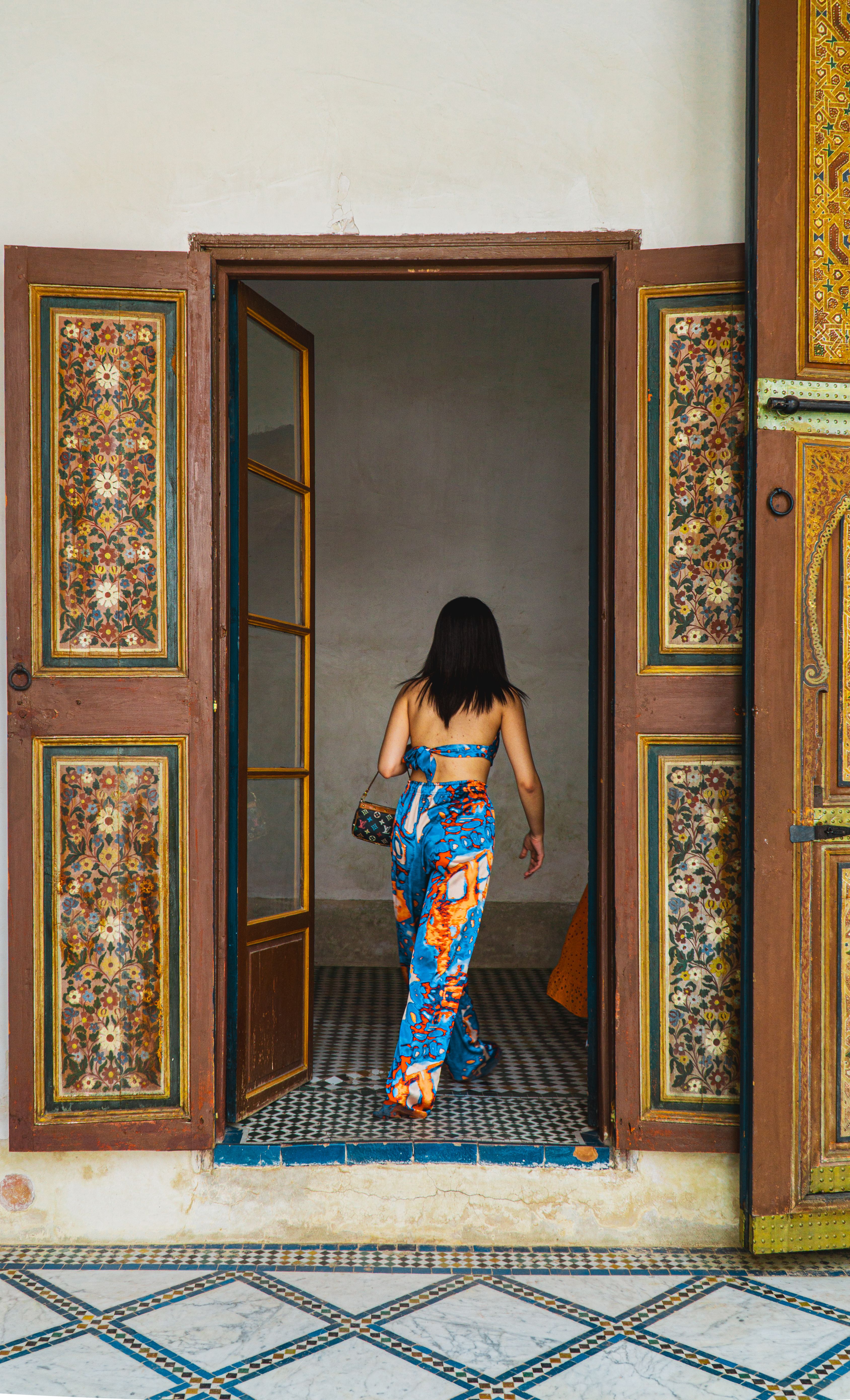 A woman in a colorful dress walking through an open door · Free Stock Photo