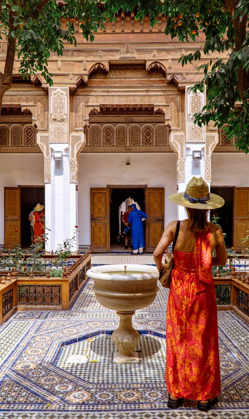 A woman in a red dress stands in front of a courtyard
