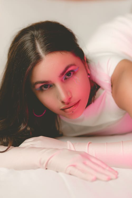 A woman laying on a bed with pink lighting