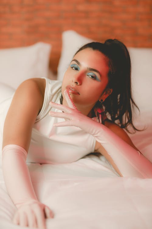 A woman laying on a bed wearing white gloves