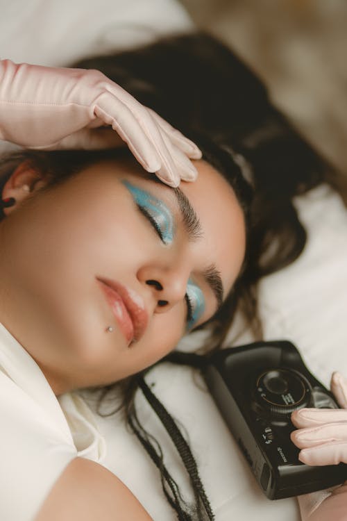 A woman laying down with her eyes closed and a camera