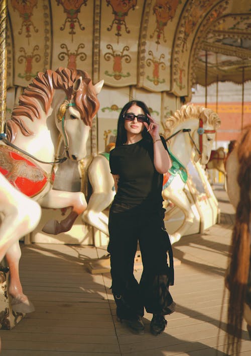 A woman in sunglasses standing next to a carousel