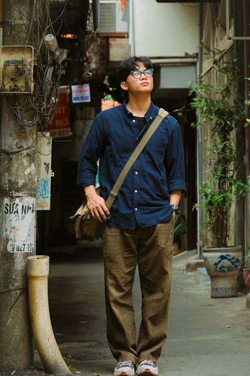 A man standing in an alleyway with a bag