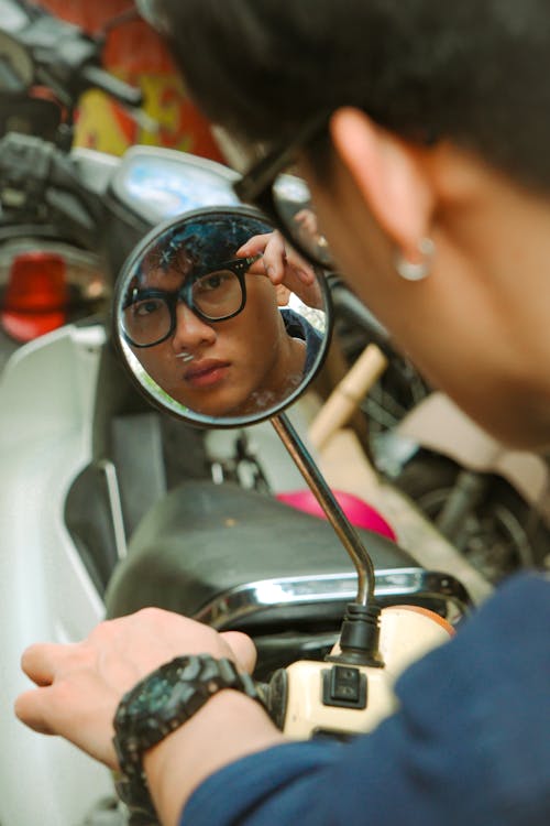 A man looking in a mirror on a motorcycle