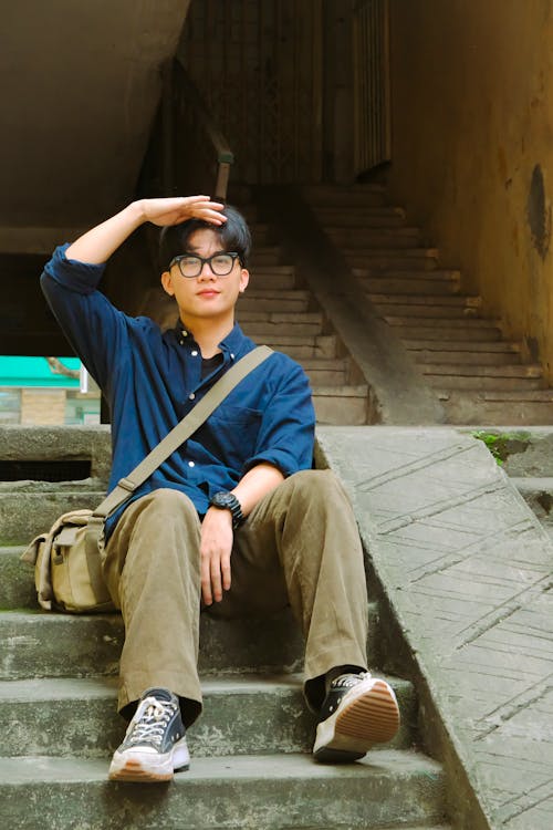 A man sitting on some steps with his hands in his pockets