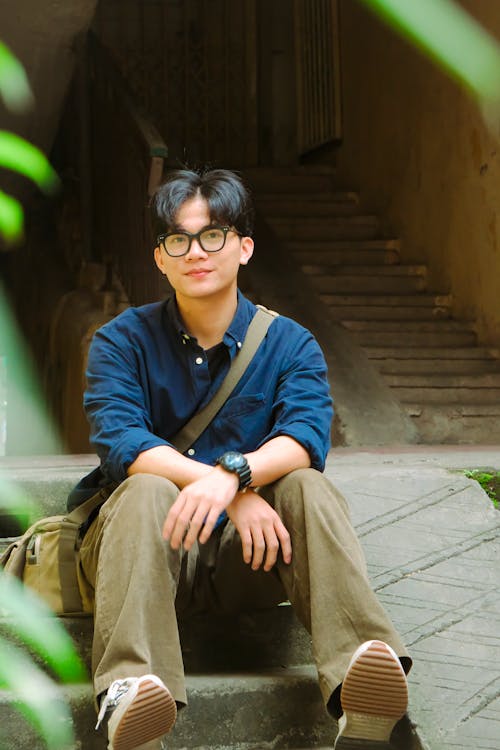 A young man sitting on some steps with a backpack