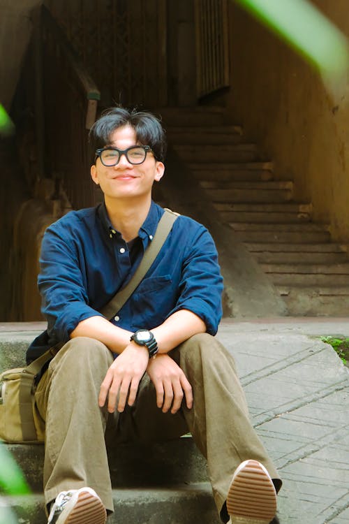 A man in glasses sitting on some steps