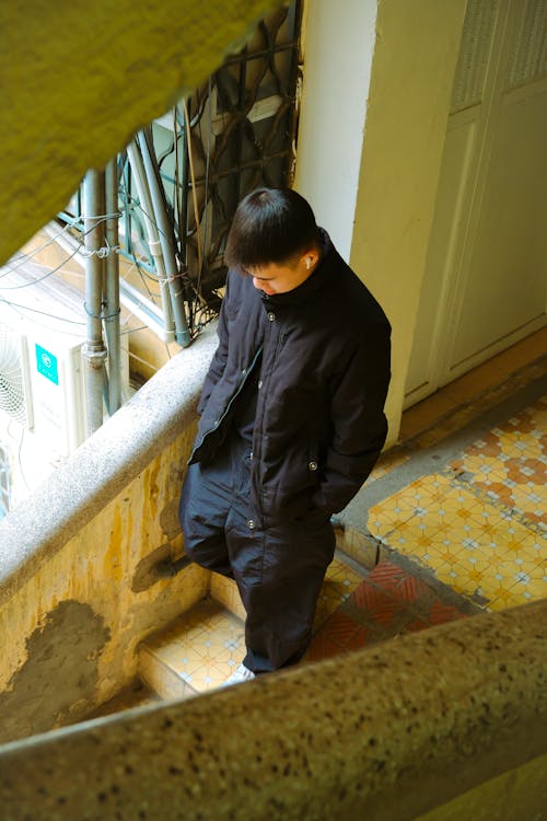 A man in a black jacket is standing on a stair