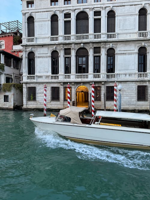 A boat is traveling down the water in front of a building