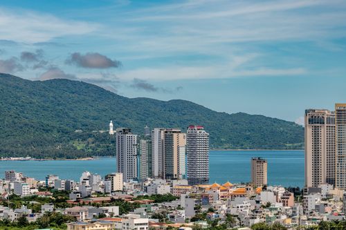 Free Cityscape of Da Nang, Vietnam with buildings, ocean, and lush mountains. Stock Photo