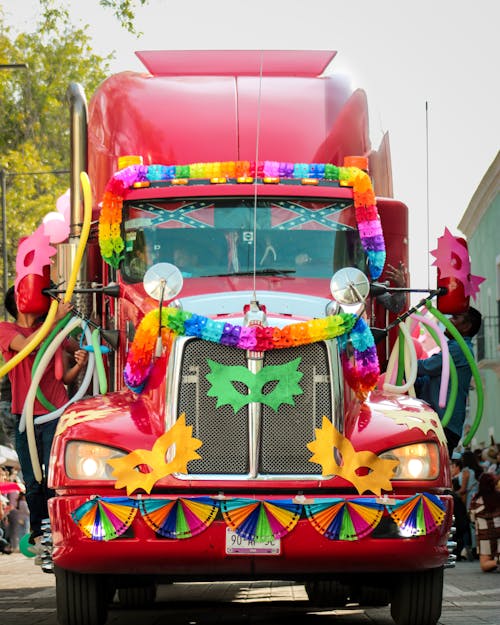 A colorful truck decorated with flowers and a parade