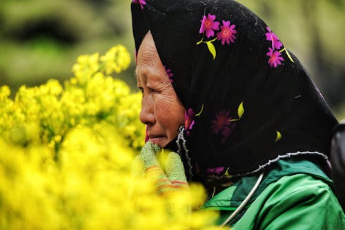 Elderly Woman among Yellow Flowers on Meadow