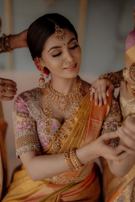 Beautiful Indian bride in traditional gold and pink sari, adorned with intricate jewelry, preparing for her wedding.