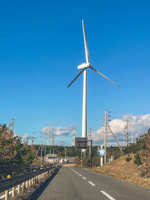 A wind turbine on a road with a blue sky