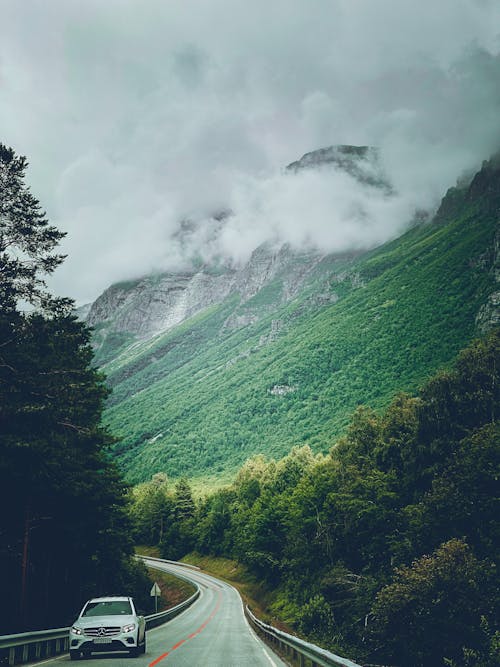 A car driving down a road with mountains in the background