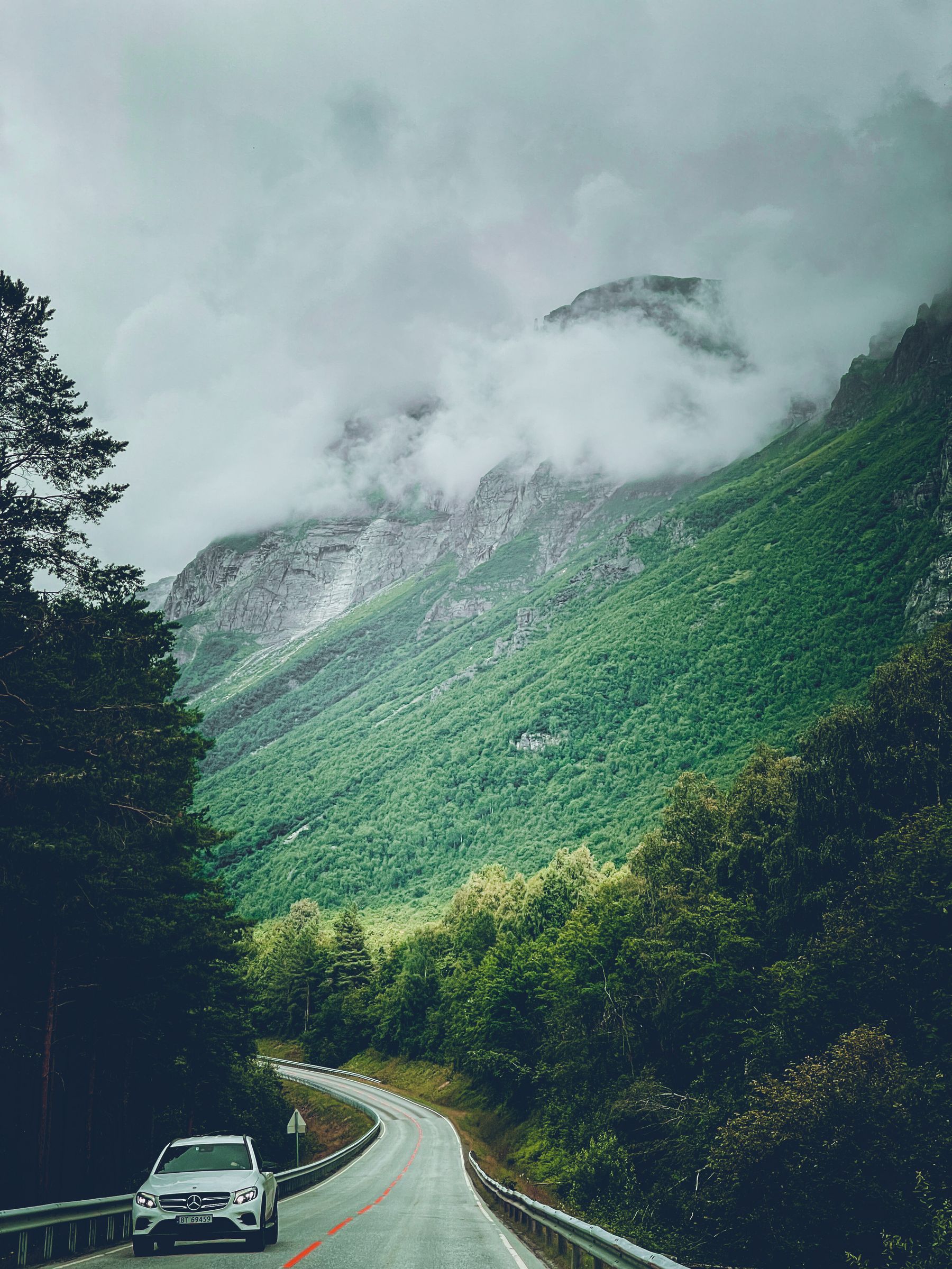 Ein Auto auf einer kurvigen Straße in bergiger Landschaft.