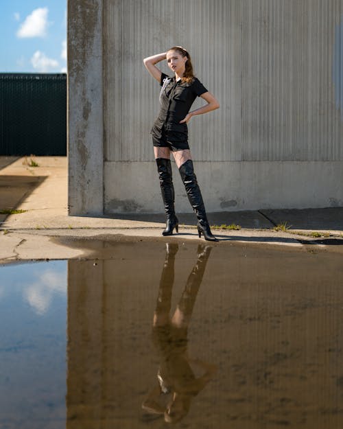 Female Model Wearing Thigh High Boots Posing behind a Puddle of Water