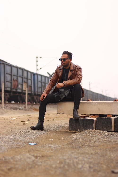 A man in a leather jacket sitting on a bench