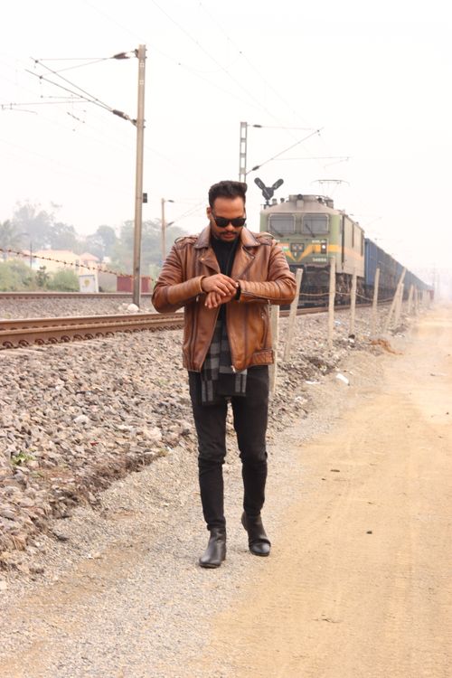 Free Man in leather jacket walking alongside train tracks in a rural setting. Stock Photo