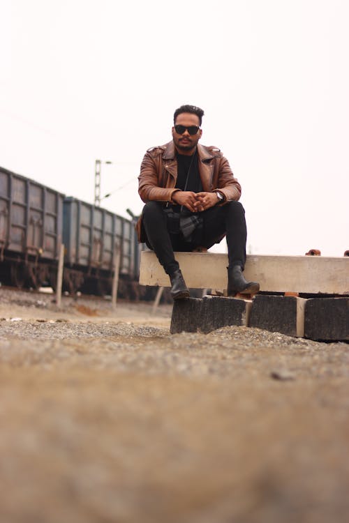 A man sitting on a bench in front of train tracks