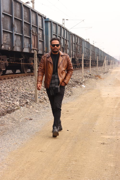 A man in a leather jacket walking down a dirt road