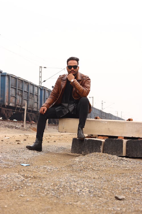 A man sitting on a bench in front of train tracks