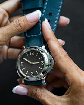 Stylish wristwatch with blue leather displayed on hands against a black background.