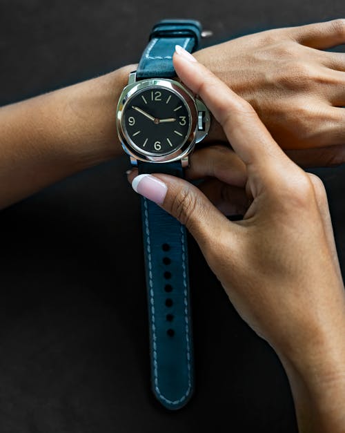 A woman's hand is holding a watch with a blue strap