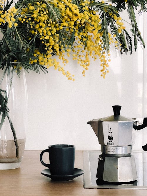 A coffee pot sits on a table next to a mug of coffee