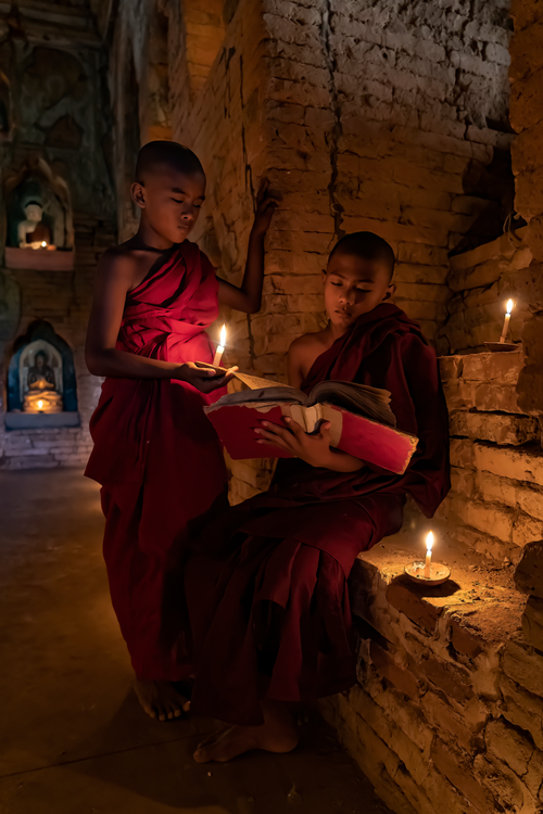 Free Two young monks reading with candles in a temple in Bagan, Myanmar. Stock Photo