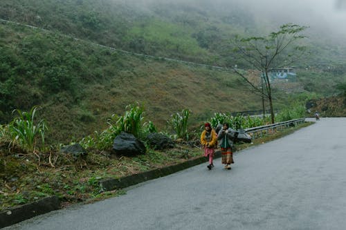 Two people walking down a road in the mountains