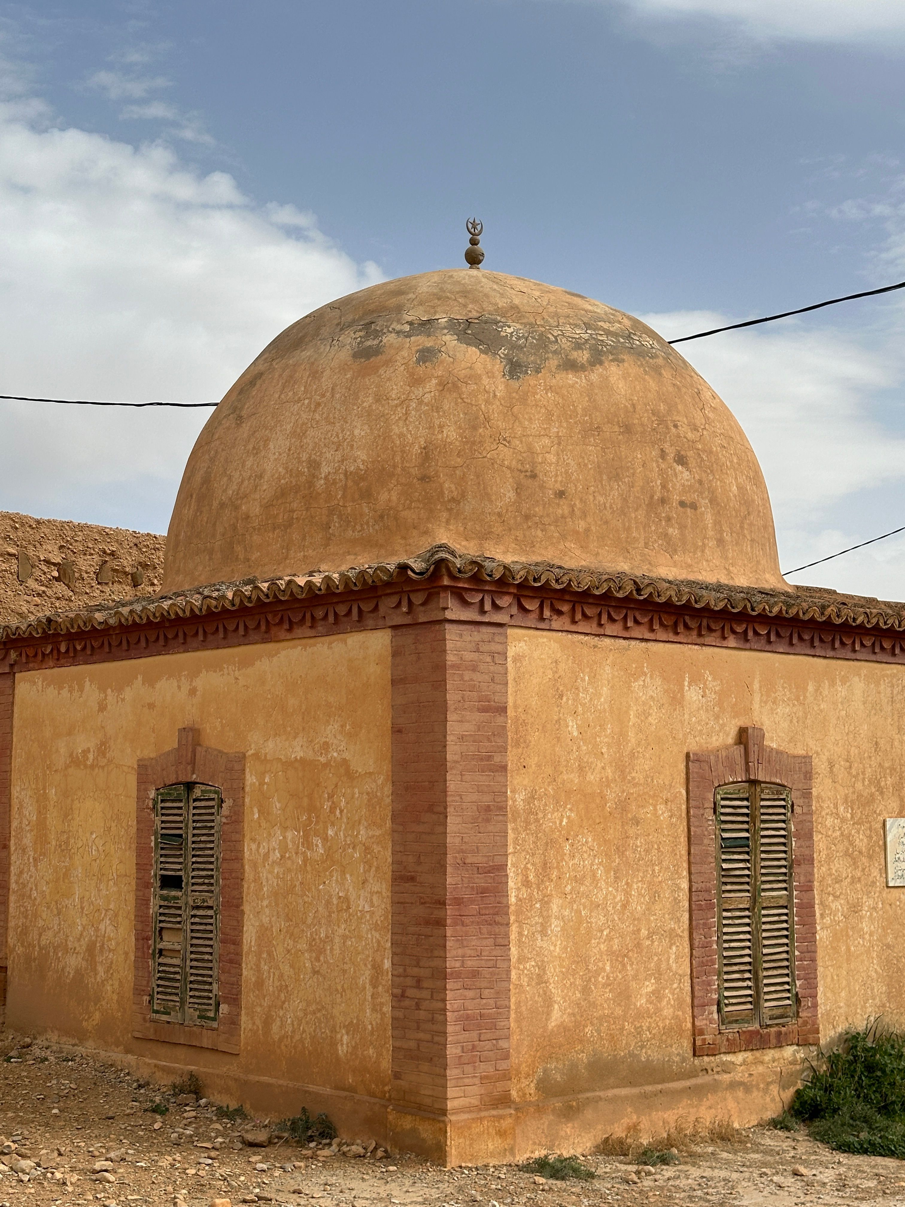 Ancient adobe dome building with brick accents in a desert setting.