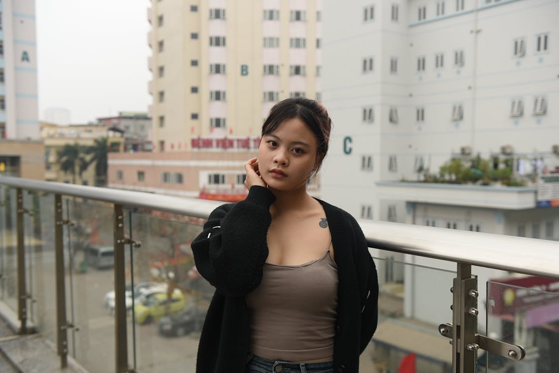 A woman standing on a balcony with buildings in the background