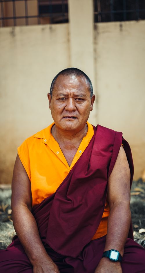 Free Portrait of a Buddhist monk sitting outdoors in traditional robes, conveying serenity and wisdom. Stock Photo