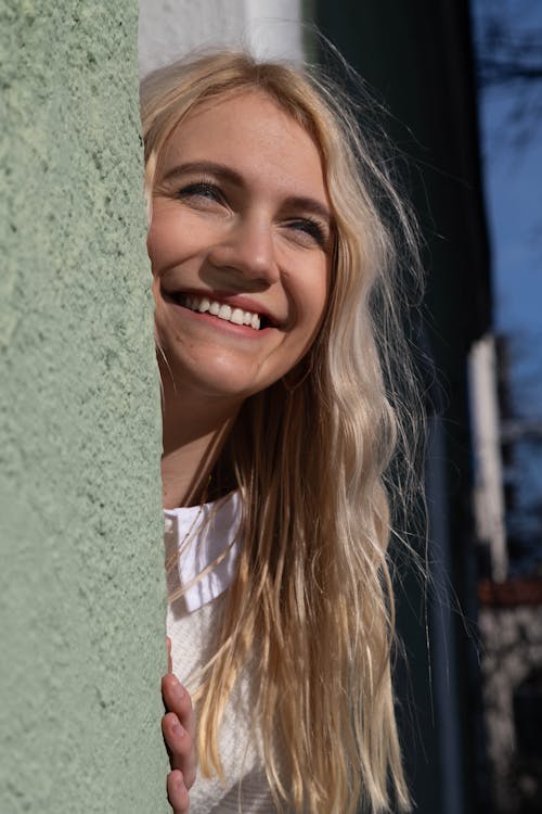 A smiling blonde woman leaning against a wall