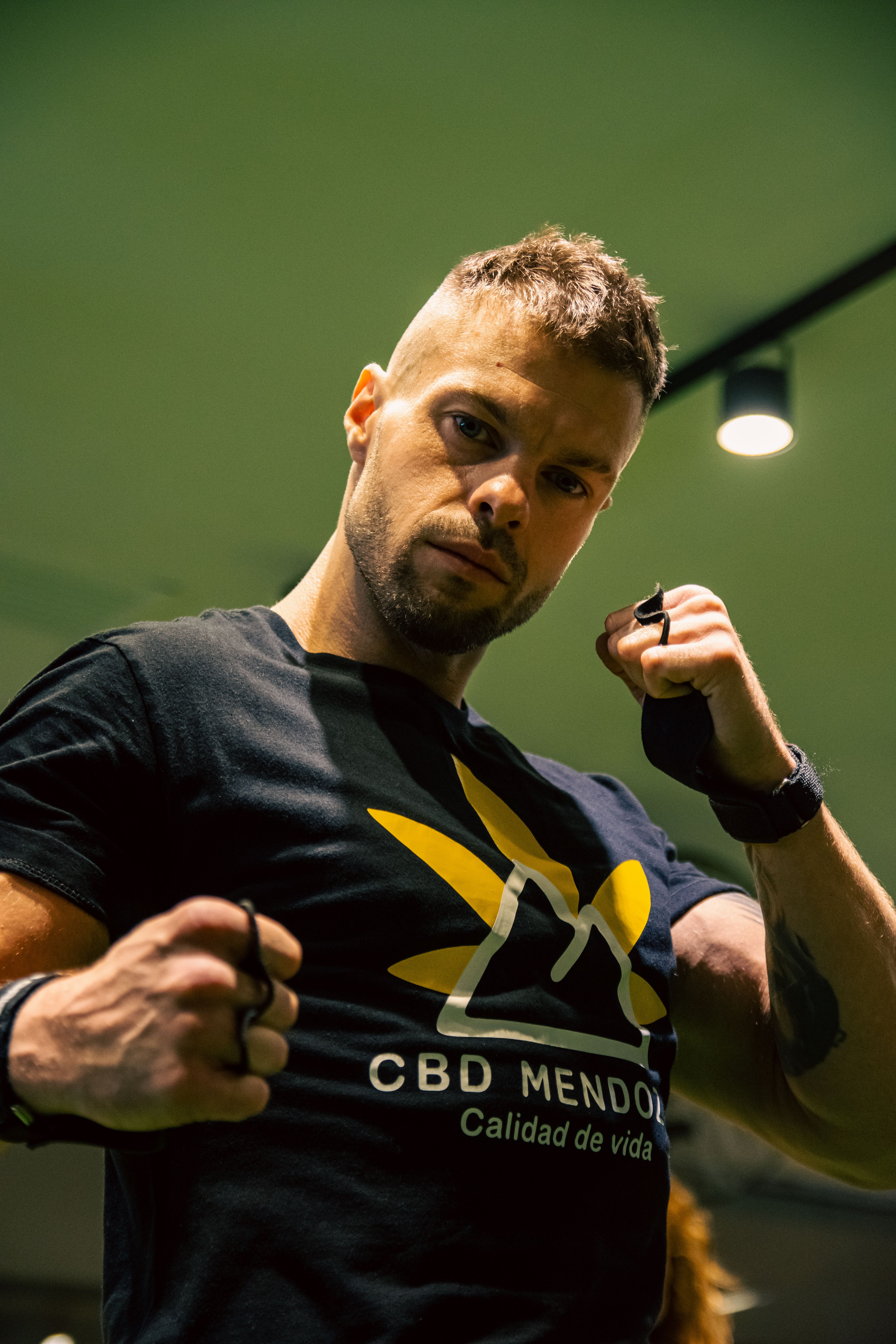 Muscular man posing with fists raised, wearing a black t-shirt. Perfect for fitness themes.