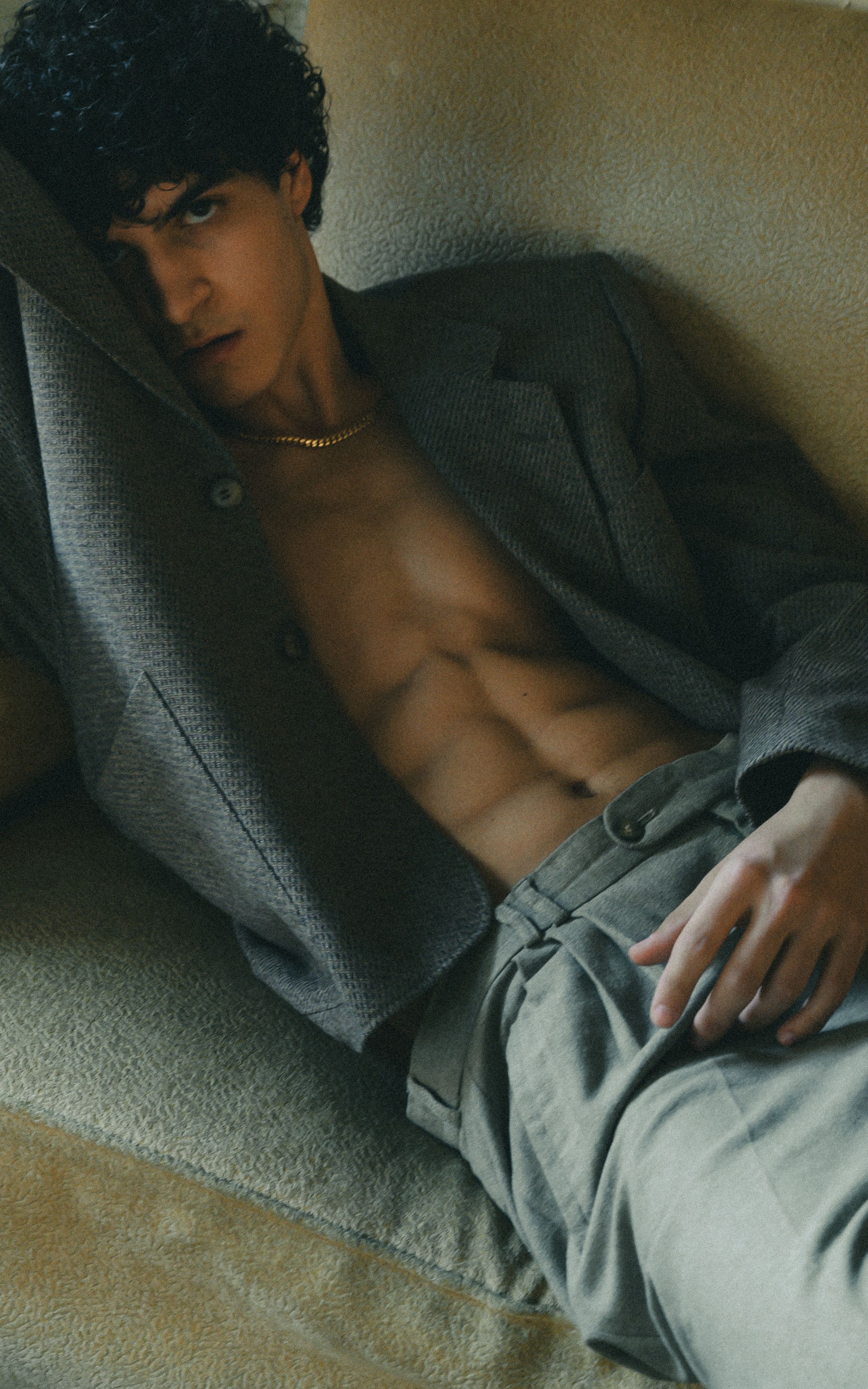Portrait of a handsome young man in a gray jacket lying indoors with a fashionable and relaxed style.