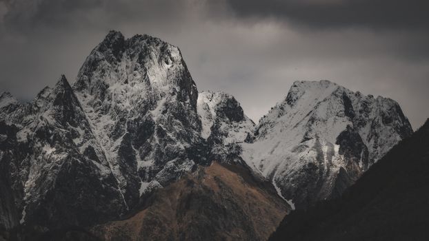 Dramatic snow-covered mountain peaks under a cloudy winter sky.