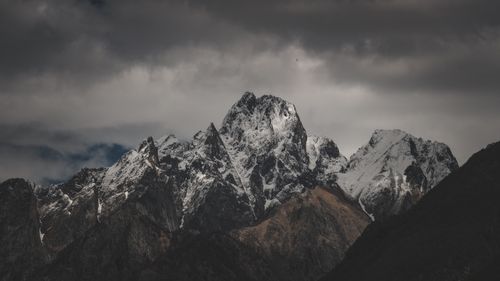 Free Dramatic snow-covered mountain peaks under a moody and cloudy sky, showcasing the beauty of nature. Stock Photo