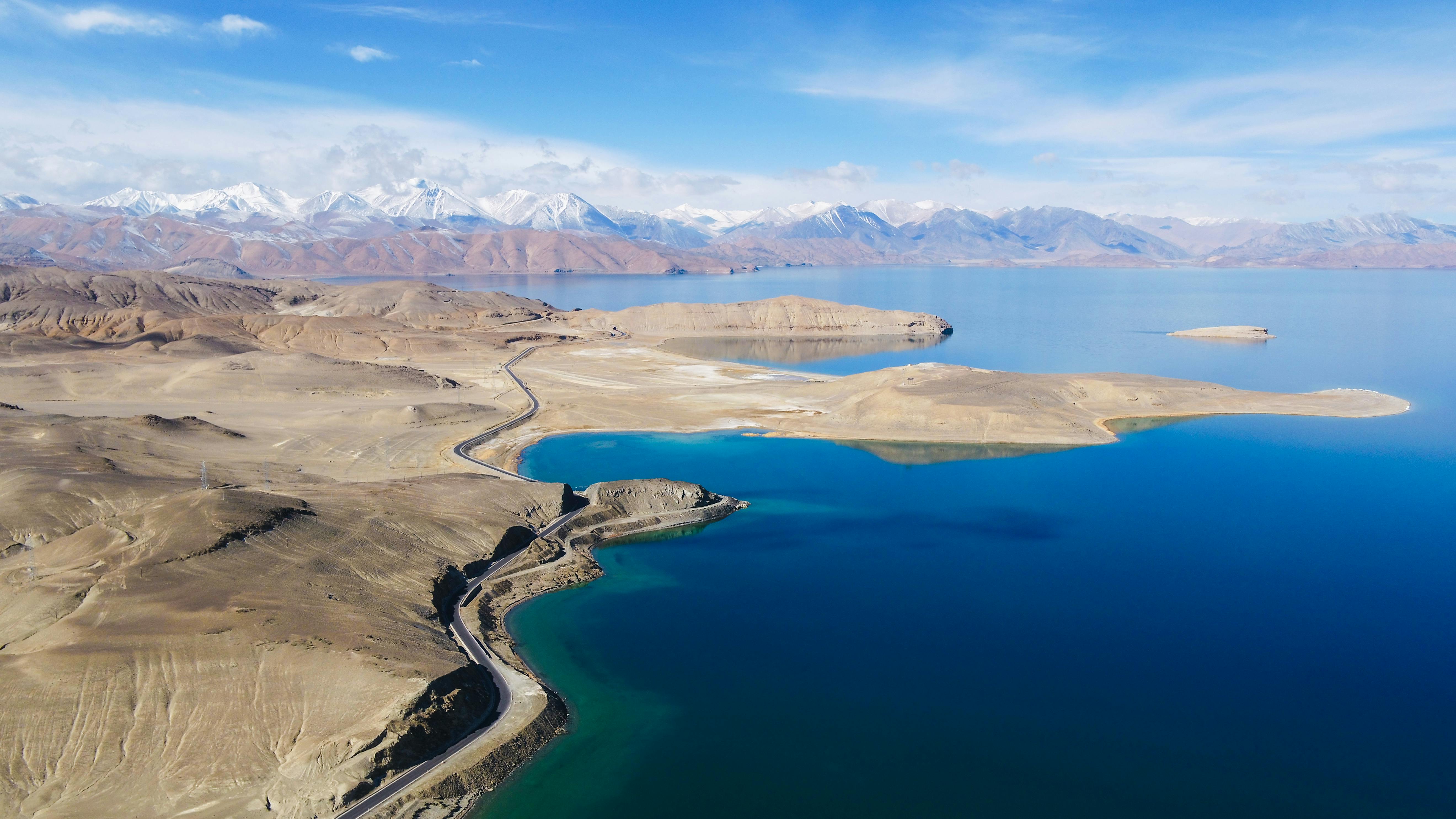 Stunning aerial shot of Tibetan mountains and a serene blue lake under clear skies.