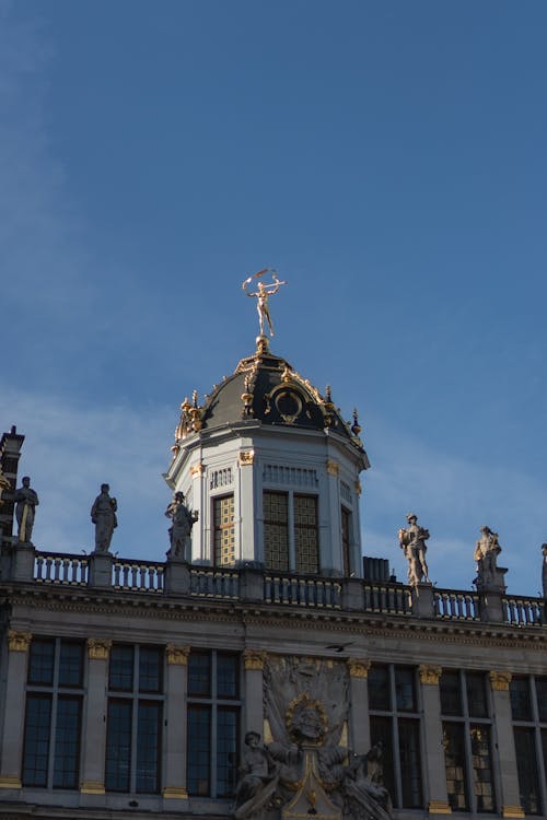 The top of a building with a clock and statues