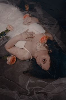 A bride in a wedding dress adorned with roses, lying down with a serene expression.