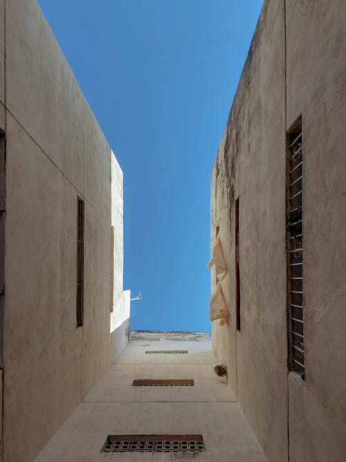 A narrow alley with windows and a blue sky