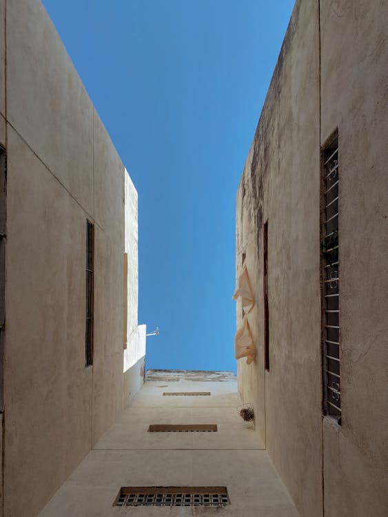 A narrow alley with windows and a blue sky