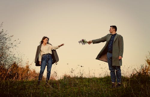 A man and woman are standing in a field with flowers