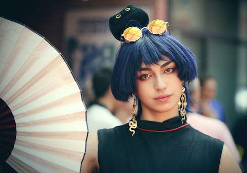 A woman with blue hair and a black and white fan