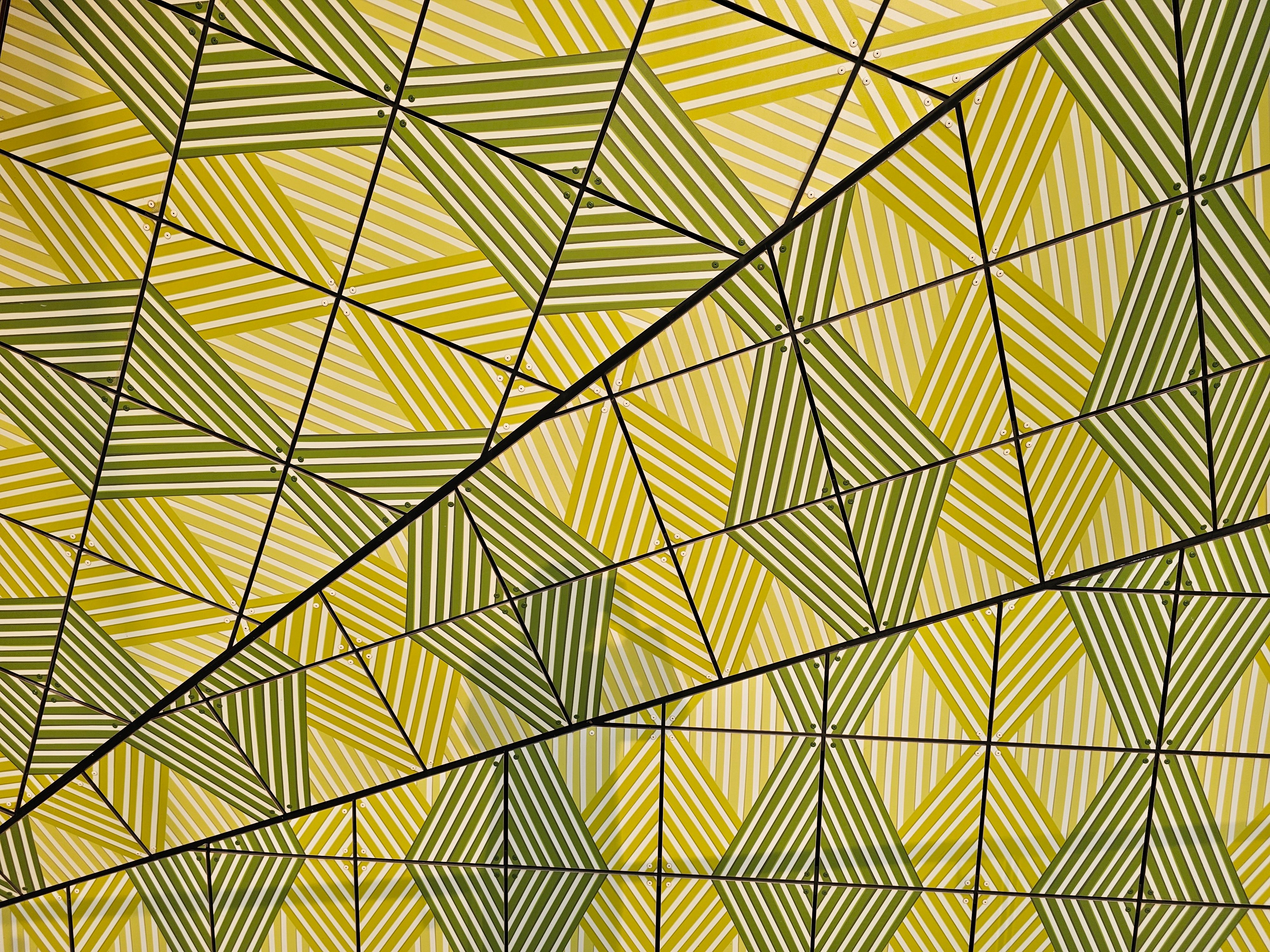 Intricate abstract pattern featuring green and yellow geometric triangles on a textured surface.