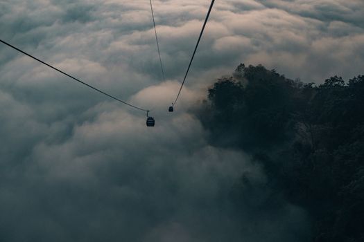 Dramatic view of cable cars traversing above the dense clouds in Butwal, Nepal.